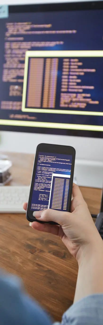 Persona che regge uno smartphone che mostra righe di codice